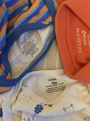 collection of infant clothing and toys, including branded