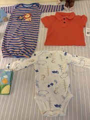 collection of infant clothing and toys, including branded